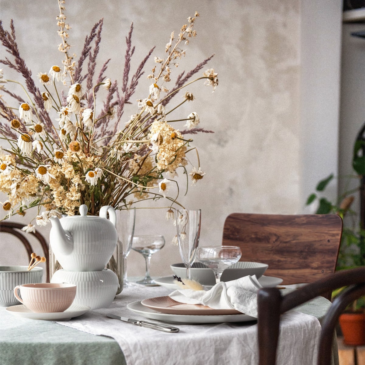 Ein gedeckter Kaffeetisch mit Blumen und Teekanne auf Stövchen