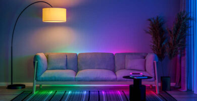 Grün-blaupink beleuchtete Couch mit einer großen Lampe mit warmem Licht darüber.
