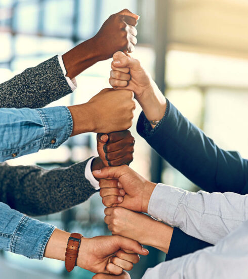Aufeinander gestapelte Fäuste von unterschiedlicher Herkunft. Symbolbild für Zusammenhalt und Mitarbeiter-Teamgeist.