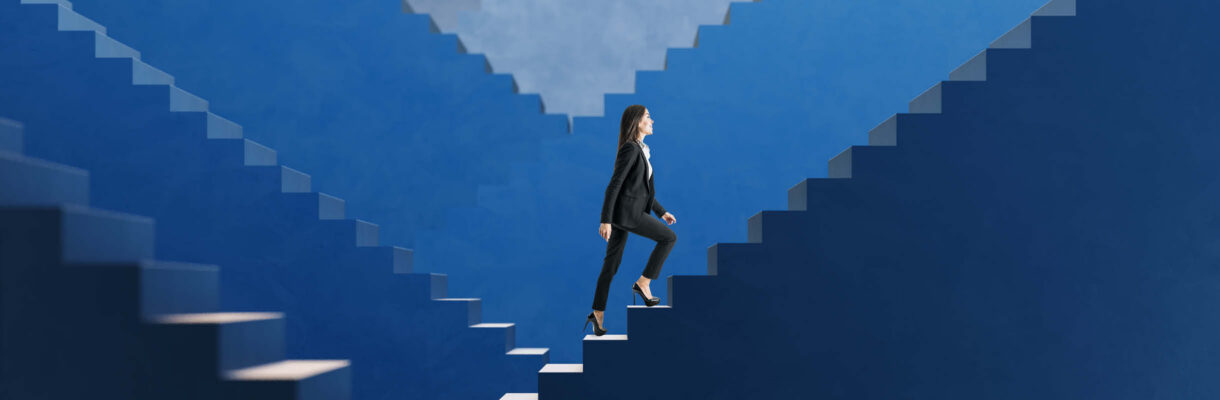 Aufbruch statt Rückblick – Geschäftsfrau steigt selbstbewusst eine blaue Treppe hinauf und symbolisiert berufliche Entwicklung, Fortschritt und neue Perspektiven.