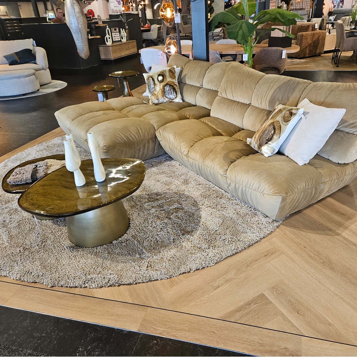 Moderne Wohnlandschaft mit beigem Sofa, Teppich und Couchtisch in Möbelhaus-Ausstellung, gemütliches Wohnzimmerdesign