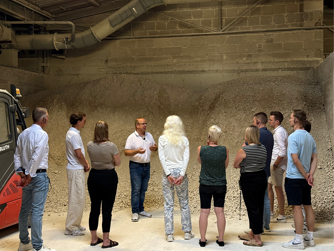 Besuchergruppe bei einer Führung vor Rohmaterial in der Keramikproduktion, mit Fokus auf Materialien für Küchenplanung, Spülen, Küchenmöbel und Designküchen.