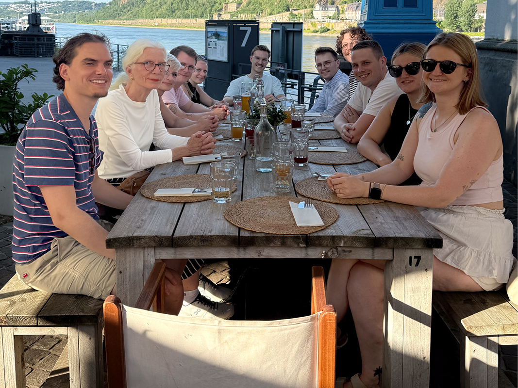 Team beim gemeinsamen Essen am Rhein nach einer Küchen- und Werksführung in Koblenz, mit Bezug zu Austausch, Küchenbranche, Küchenstudio und Küchenplanung.