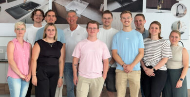 Teamfoto einer Besuchergruppe im Küchenstudio vor Ausstellungswänden mit Spülen und Armaturen als Inspiration für Küchenplanung, Küchenmöbel und moderne Designküchen.