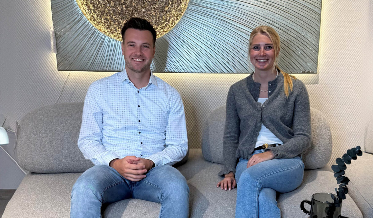 Mitarbeiter von Möbel van Weyck im persönlichen Gespräch auf einem modernen Sofa vor dekorativer Wandgestaltung – individuelle Beratung rund um Möbel, Küchenstudio und professionelle Küchenplanung.